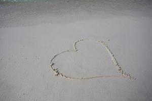 harten getekend op het zand van een strand foto