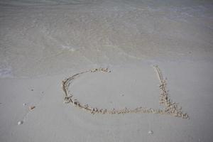 harten getekend op het zand van een strand foto