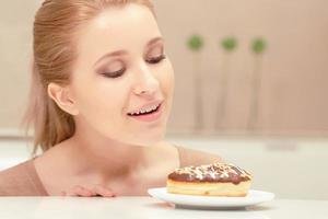 glimlachende dame kijkt naar donut met de intentie om te eten