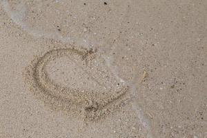 harten getekend op het zand van een strand foto