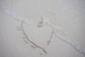 harten getekend op het zand van een strand foto