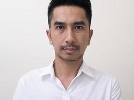 portret van een jonge grappige aziatische man met een wit overhemd die naar de camera kijkt? foto
