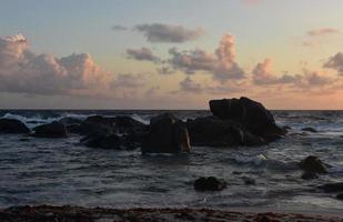 golven beuken op rotsen bij zonsopgang in aruba foto