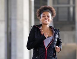 glimlachende jonge vrouw die met oortelefoons in openlucht loopt foto