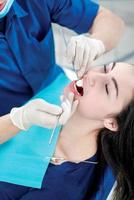 het controleren van de tanden van de patiënt. tandarts die tandheelkundige instrumenten houdt foto