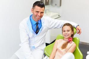 tandarts onderzoekt kleine meisjes tanden in de stoel van de tandarts