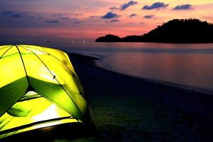 groene tent op het strand bij zonsondergang foto