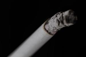 brandende sigaret met rook op zwarte achtergrond foto