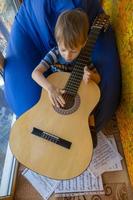 kleine jongen speelt gitaar en zingt op het balkon foto