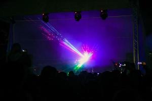 paarse laser neonstralen. menigte van mensen die kijken naar lasershow op straatfestival. foto