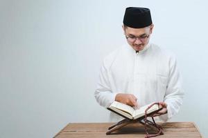 jonge aziatische moslim man die koran leest foto