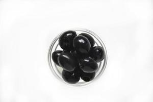 zwarte olijven in een witte en glazen pan op een witte achtergrond. foto