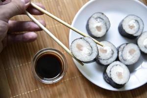genomen met stokjes sushi met tonijn om te eten. heerlijke visrol. rijst sushi roll op een mat. foto
