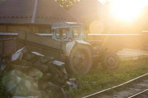 Russische oude tractor in het dorp in de bergen met de zomerzonsondergang foto