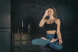 charmant meisje in een sportuniform doet yoga in een oude kamer met een open haard en kaarsen foto