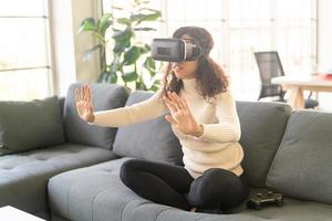 Latijnse vrouw die een virtual reality-headset gebruikt op de bank foto