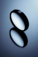 minimaal stillevenbeeld van een rond voorwerp op glanzend oppervlak in blauw zwart-wit. foto