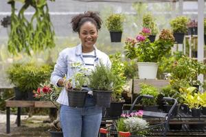 jonge afrikaanse klant kiest rozemarijn- en salieplant uit de plaatselijke tuincentrumkwekerij met winkelwagen vol zomerplant voor weekendtuinieren en buitenactiviteiten foto