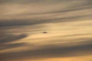 vliegtuig in de avondlucht in lichtgevende horizon. het gaat op vakantie foto
