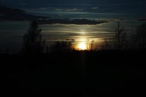 zonsondergang met brandende lucht achter de bomen. foto