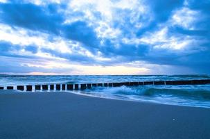zonsondergang op het strand van de Oostzee. kribben reiken tot in de zee. blauw uur foto