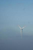 windmolen in mistig landschap. hernieuwbare energie voor een milieubewuste toekomst foto