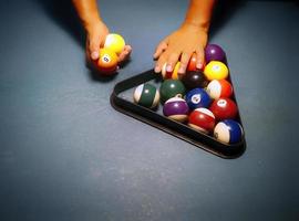 handen voorbereiden poolballen in driehoekrek op de biljarttafel foto