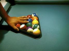 hand poolballen voorbereiden in driehoekrek op de biljarttafel foto