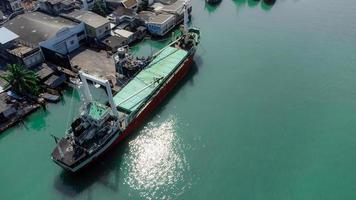 vissersboten in een vissersdorp reflecterend op het water. het leven van een vissersdorp aan de kust van songkhla, thailand vanuit het vogelperspectief van de drone. foto