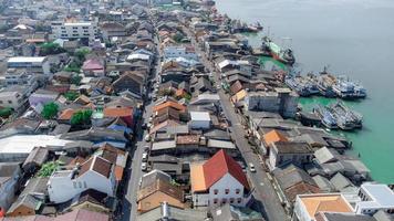 vissersboten in een vissersdorp reflecterend op het water. het leven van een vissersdorp aan de kust van songkhla, thailand vanuit het vogelperspectief van de drone. foto