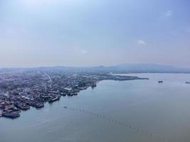 vissersboten in een vissersdorp reflecterend op het water. het leven van een vissersdorp aan de kust van songkhla, thailand vanuit het vogelperspectief van de drone. foto