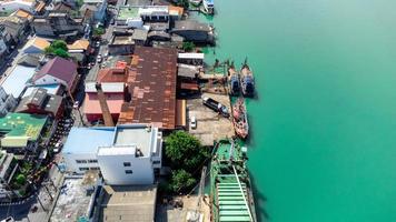 vissersboten in een vissersdorp reflecterend op het water. het leven van een vissersdorp aan de kust van songkhla, thailand vanuit het vogelperspectief van de drone. foto