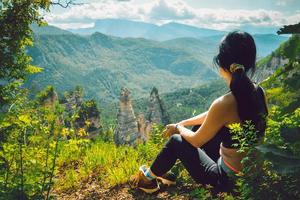 achteraanzicht sportief kaukasisch zitten ontspannen genieten van het panorama van de schilderachtige groene bergen in Georgië na het wandelpad de top bereiken buitenshuis foto