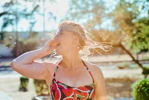 lachende emotionele blonde vrouw met nat haar die waterspatten maakt. vakantie, geluk, plezier, zomer, vrije tijd concept foto