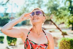 lachende emotionele blonde vrouw met nat haar die waterspatten maakt. vakantie, geluk, plezier, zomer, vrije tijd concept foto