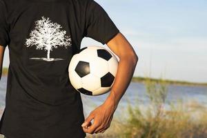 man met een voetbal op het veld aan de rivier foto