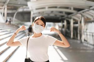 gelukkige glimlach jonge volwassen zakelijke aziatische vrouw draagt een gezichtsmasker om het virus corona of covid19 te beschermen. foto