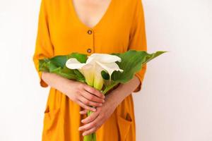 een vrouw houdt een boeket calla's in haar handen foto