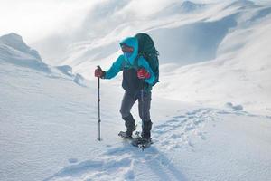 een wandelaar loopt op sneeuwschoenen in de sneeuw foto