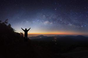 melkwegstelsel en silhouet van een staande gelukkige man op doi inthanon chiang mai, thailand. foto