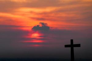 silhouet van kruis over vage zonsondergangachtergrond foto