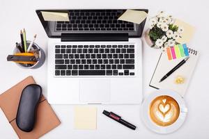 bovenaanzicht laptop of notebook werkruimte kantoor en latte koffie op witte tafel foto