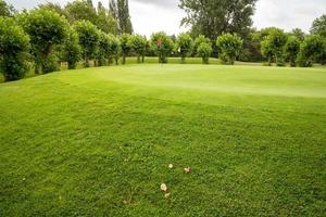 golfbaan met gras en wolken in de lucht foto