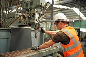 portret van een professionele ingenieur in de zware industrie met uniform, bril en helm in een staalfabriek. industriële specialist die zich in metaalconstructiefaciliteit bevindt. foto