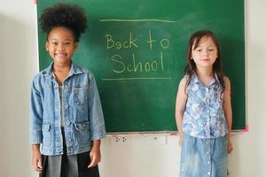 gelukkige kleine meisjes tegen schoolbord met terug naar school foto