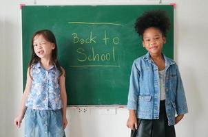 gelukkige kleine meisjes tegen schoolbord met terug naar school foto