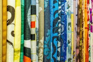 brede selectie van verschillende kleuren textiel zijden stoffen kleding lag in de rij in draperie winkel foto