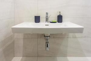 zeep- en shampoodispensers in de buurt van keramische waterkraangootsteen met kraan in dure zolderbadkamer of keuken foto