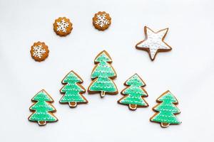 handgemaakte feestelijke peperkoekkoekjes in de vorm van sterren, sneeuwvlokken, mensen, sokken, personeel, wanten, kerstbomen, harten voor kerstmis en nieuwjaarsvakantie op witboekachtergrond foto