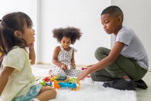 kinderen spelen met hun vrienden op de vloer, kinderen meisjes en jongen spelen speelgoed en spel in de woonkamer foto